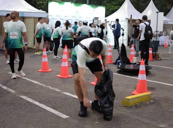 014 Foto 3 Seorang Peserta Lari memungut Sampah sebagai salah satu kegiatan pelestarian lingkungan di acara Sharp Run For The Future